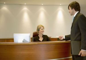 Businessman Standing at a Reception Desk Giving a Business Card to the Receptionist